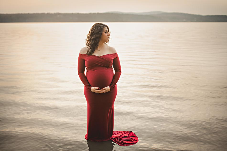 pregnant woman holding stomach standing in water
