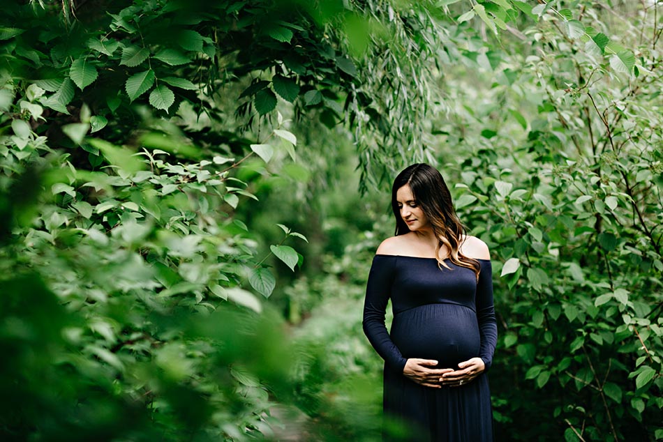 pregnant woman holding stomach in forest
