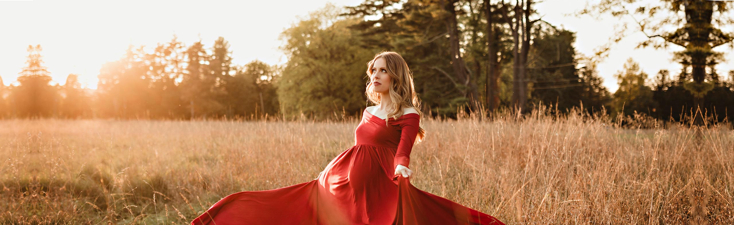 pregnant woman in red dress standing in field