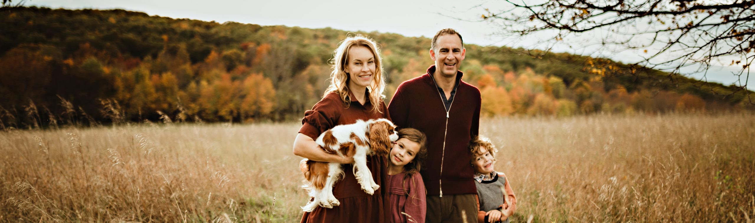 family standing with dog standing in a field